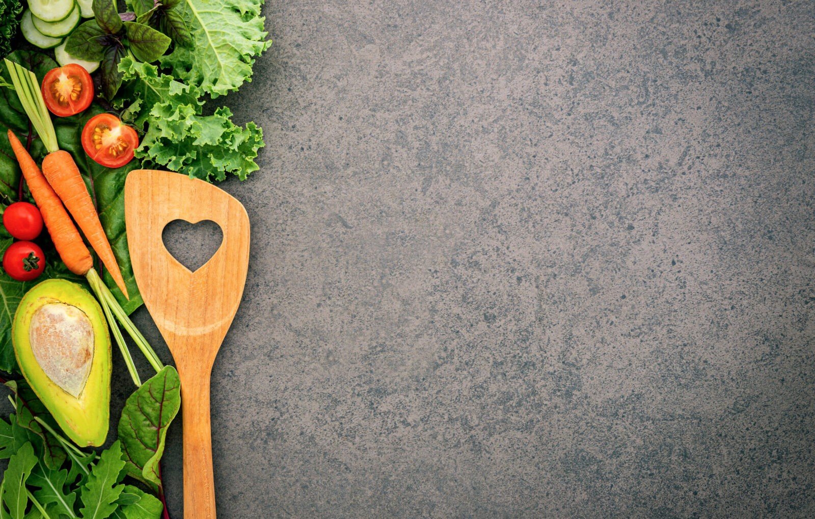 fruits and vegetables next to a wood spoon on a counter top